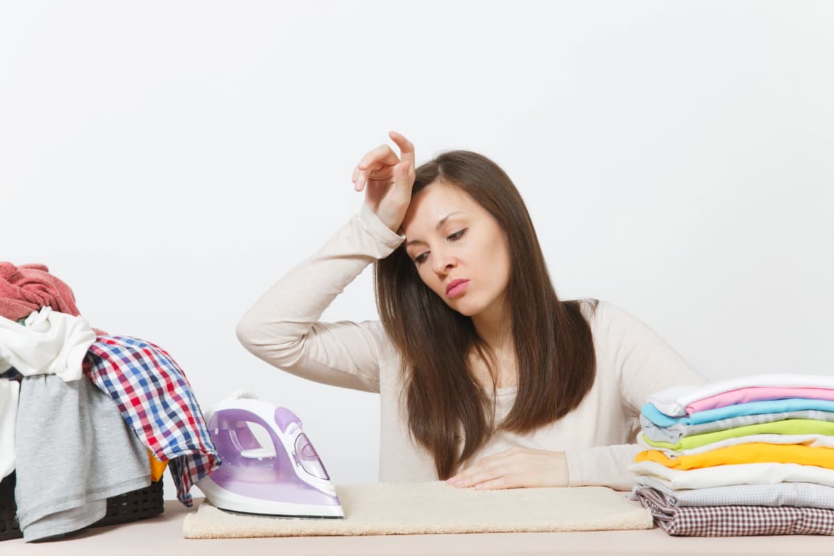 Vermoeide vrouw bij het strijken